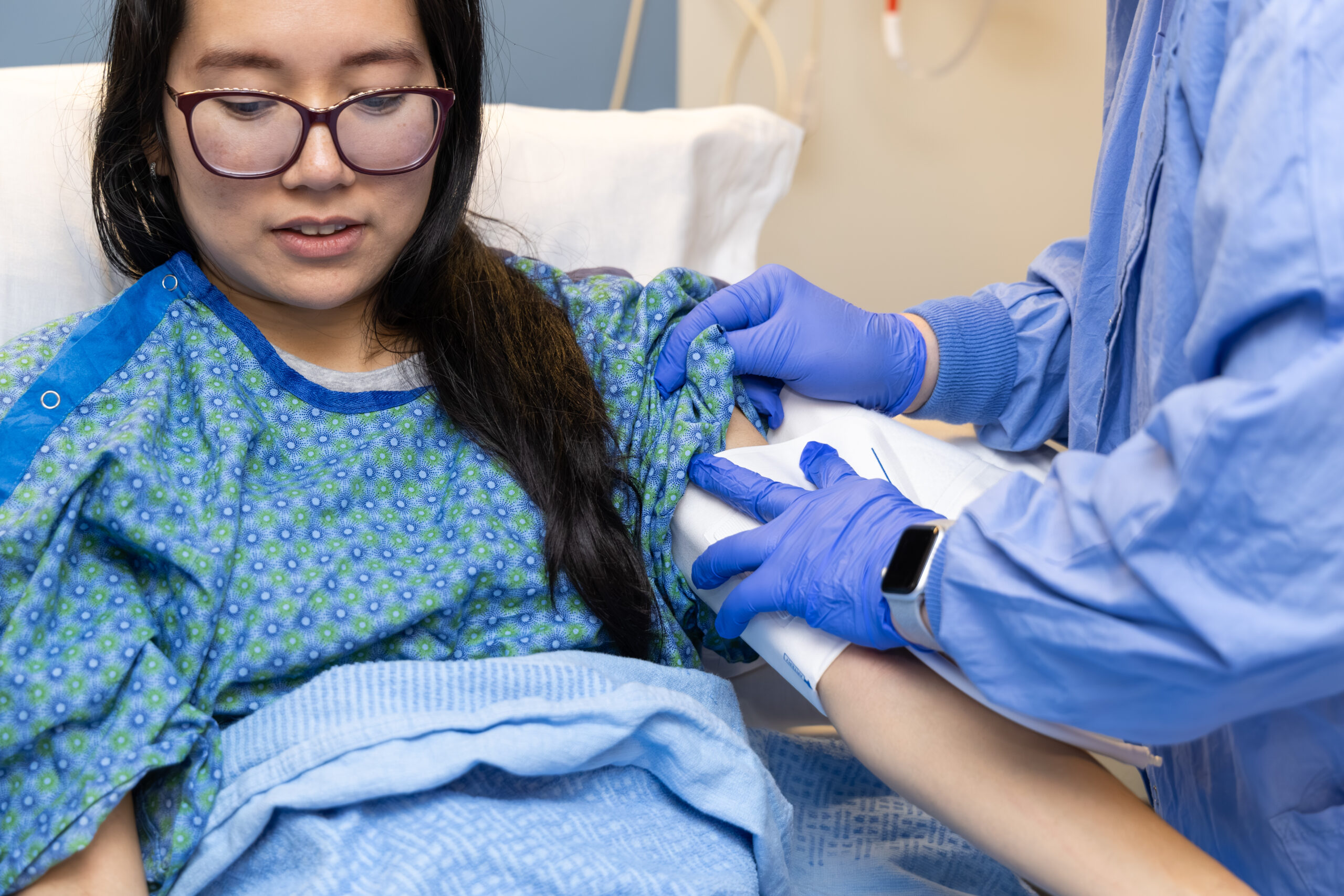 Nurse demonstrating a clinical procedure on a patient’s arm in a hospital setting