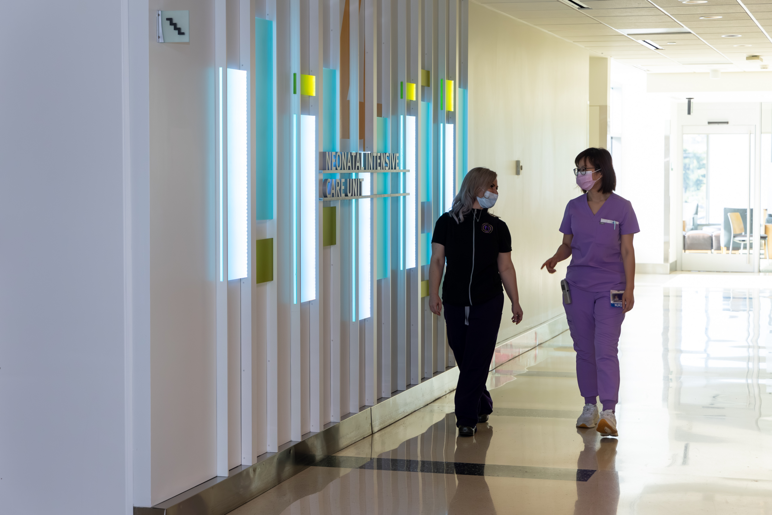 Two nurses walking and talking together in a hospital hallway